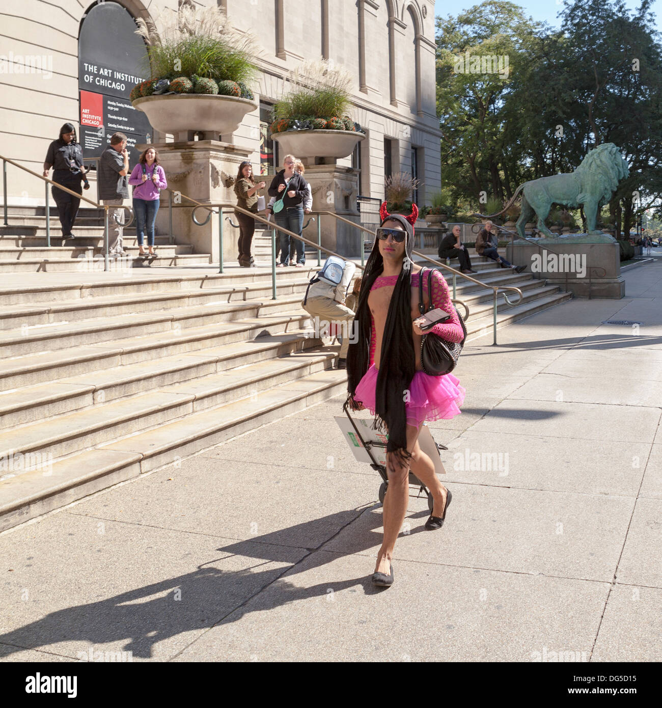 Un uomo vestito con una rosa frilly outfit passeggiate sul marciapiede attraendo molti guarda nel centro cittadino di Chicago. Foto Stock