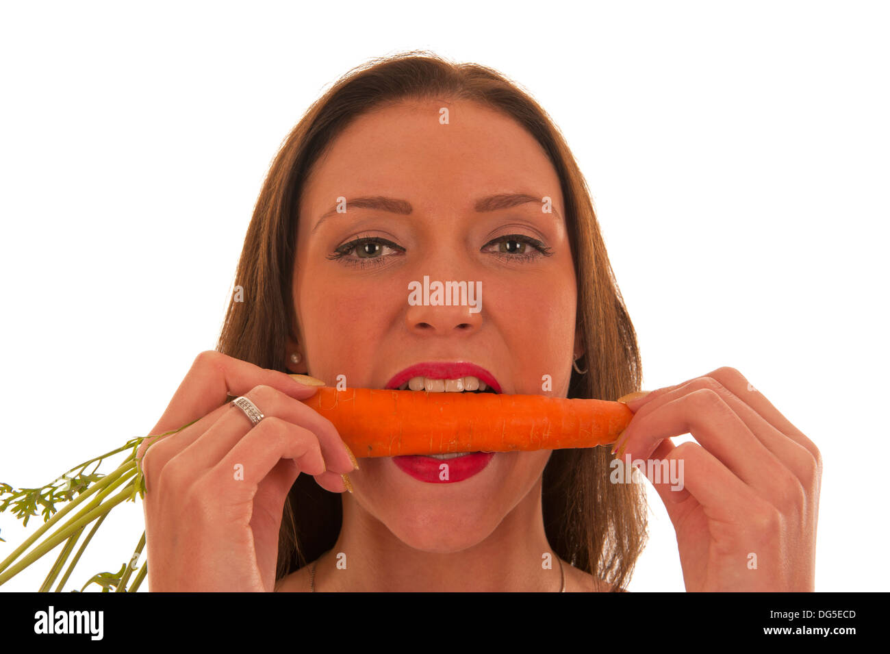Giovane ragazza mette i suoi denti in una carota arancione Foto Stock