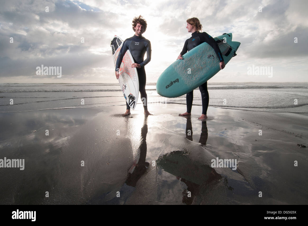 Coppia permanente sulla spiaggia con tavole da surf, uno ha una telecamera Gopro attaccata alla tavola da surf Foto Stock