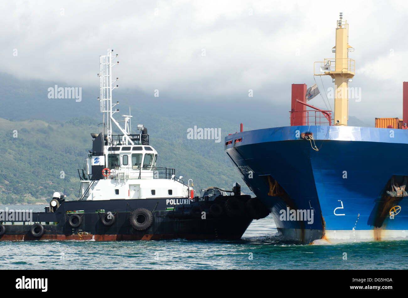 Barche rimorchiatore aiutando una nave da carico per interrompere a Sao Sebastiao porta, Sao Paulo membro a riva, Brasile Foto Stock