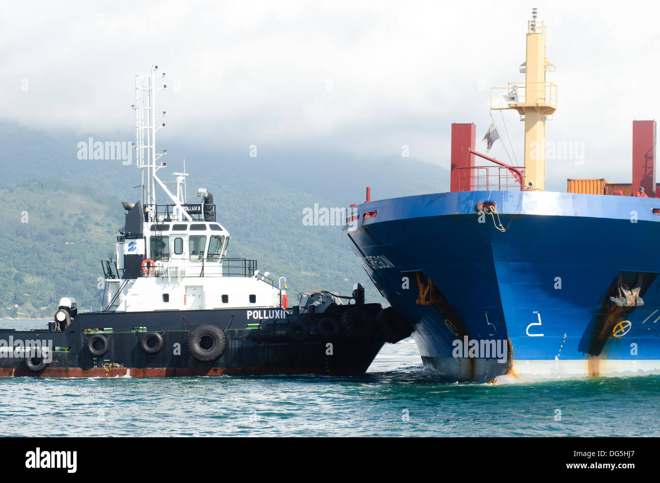 Barche rimorchiatore aiutando una nave da carico per interrompere a Sao Sebastiao porta, Sao Paulo membro a riva, Brasile Foto Stock