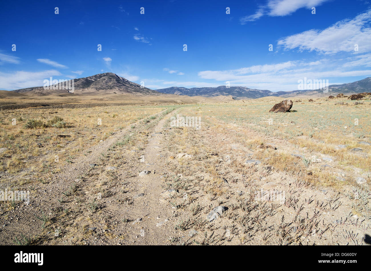 Doppia via strada di ghiaia che non riesce a ottenere molto traffico voce verso lontane montagne del Nevada Foto Stock