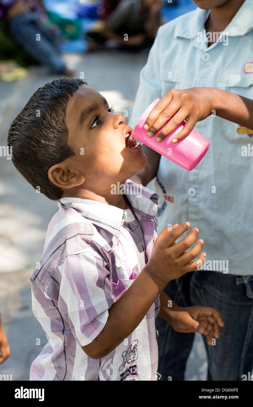 Ragazzo indiano stato dato acqua potabile a Sathya Sai Baba mobile ospedale outreach. Andhra Pradesh, India Foto Stock