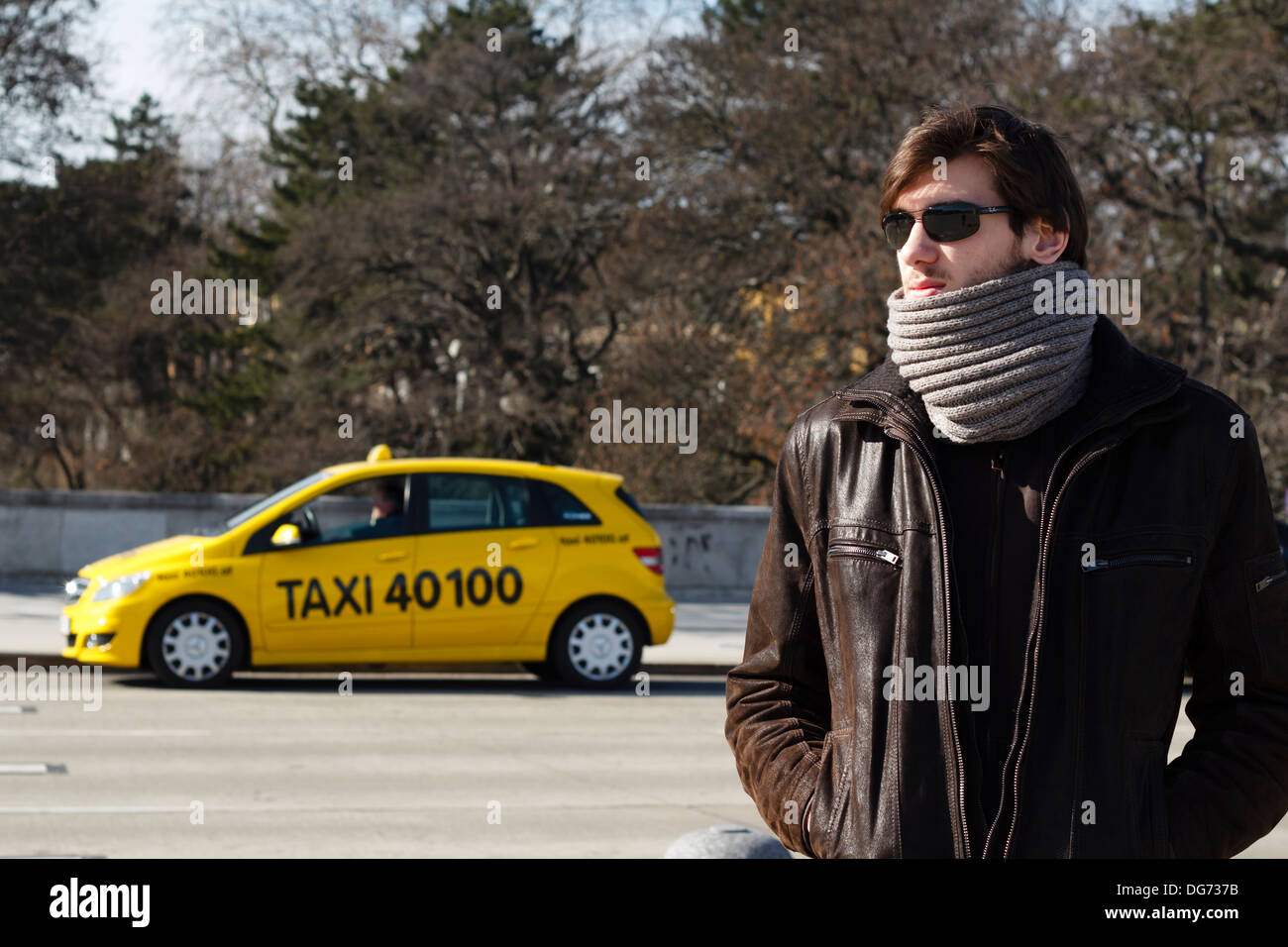 Giovane uomo esprimendo fiducia e freddezza con taxi giallo sullo sfondo di Vienna in Austria Foto Stock