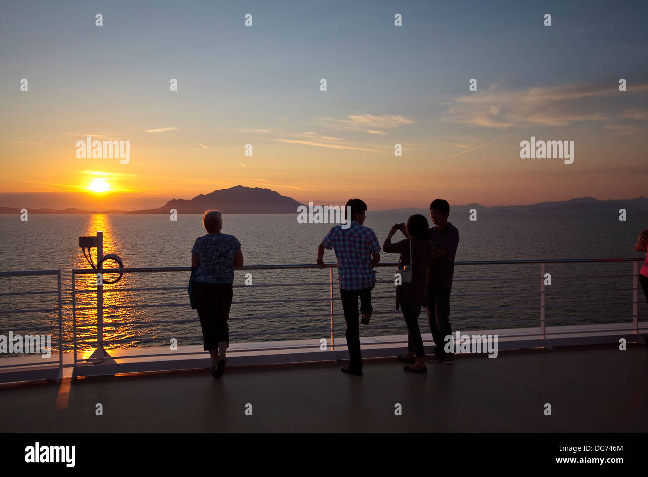 Passeggeri a guardare un tramonto da una nave vicino a Vancouver, B.C. Foto Stock