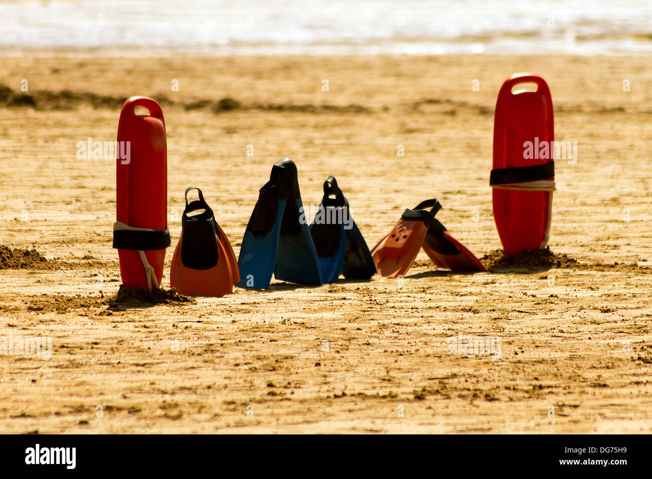 Bagnino e pinne in piedi nella sabbia Foto Stock