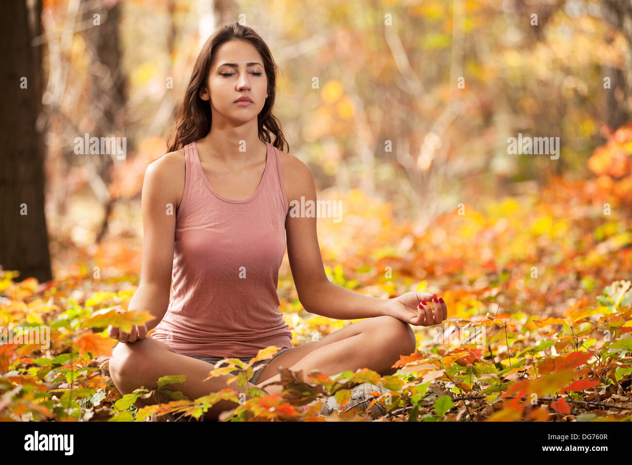 Bella ragazza giovane meditando in autunno park Foto Stock