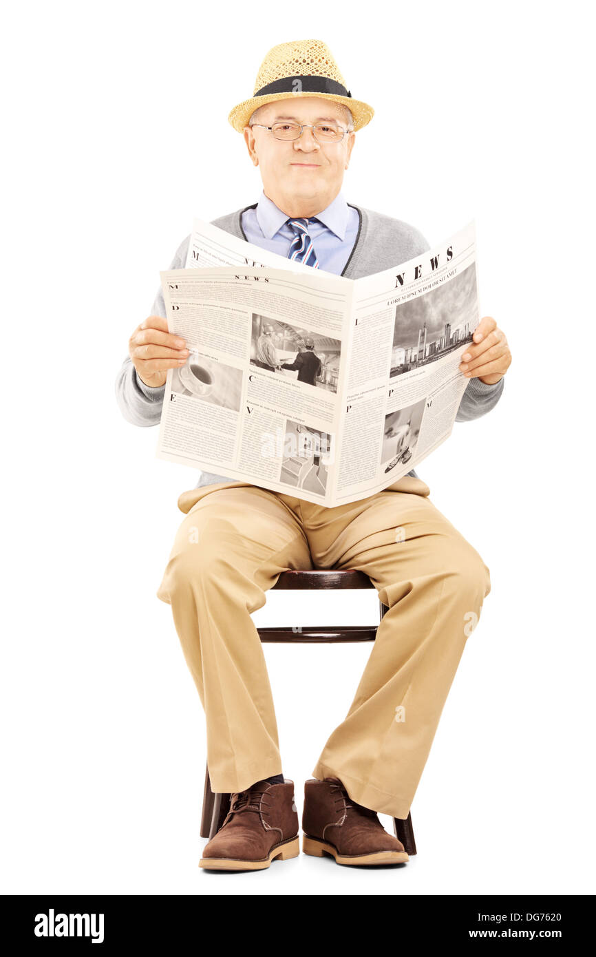 Senior gentleman su una sedia in legno tenendo un giornale e guardando la fotocamera Foto Stock