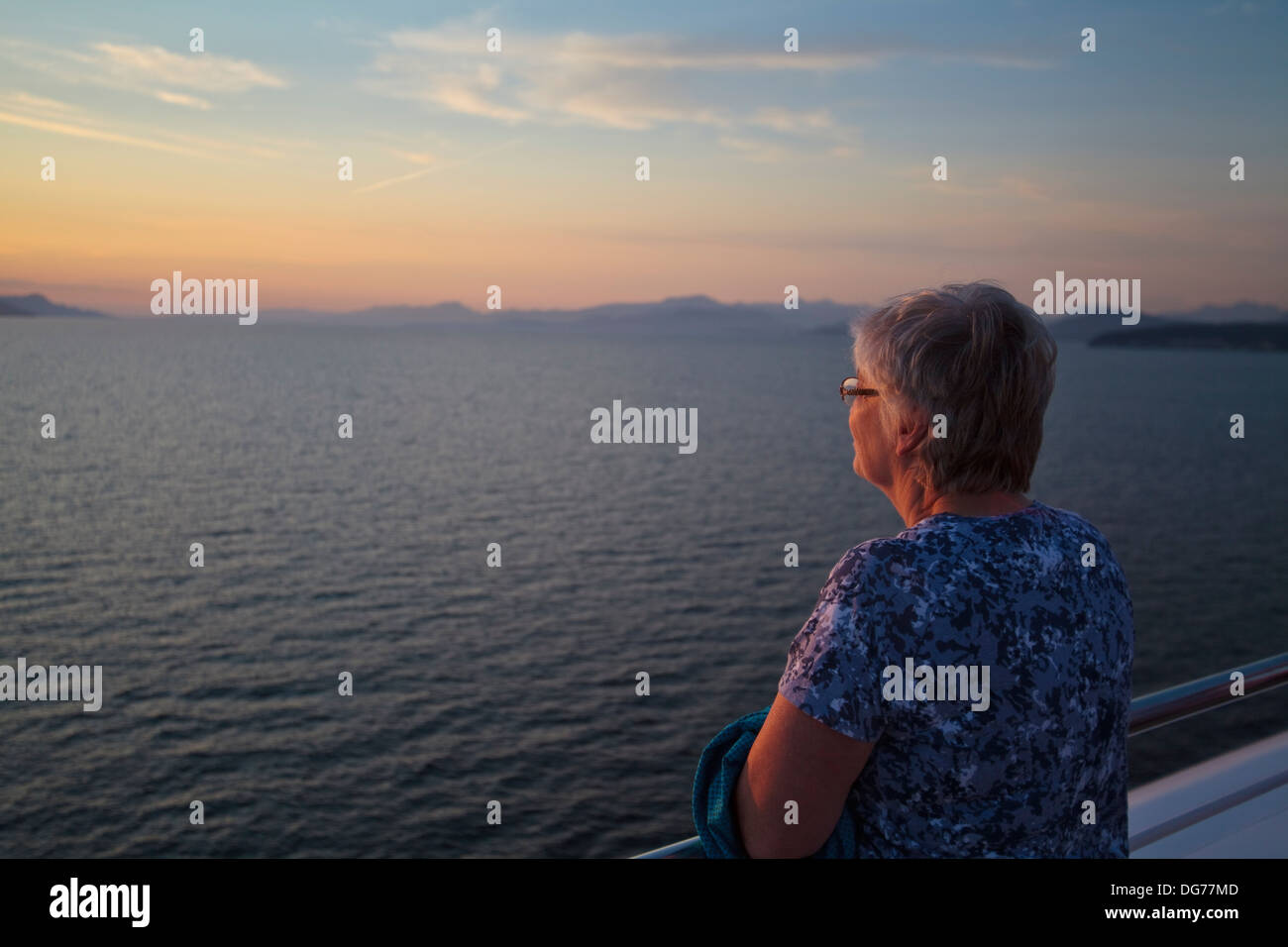 Donna guardando un tramonto da una nave appena al di fuori della città di Vancouver. Foto Stock