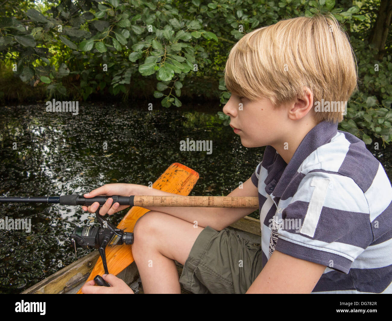 Un ragazzo di pesca dalla barca a remi in un lago in inglese Foto Stock