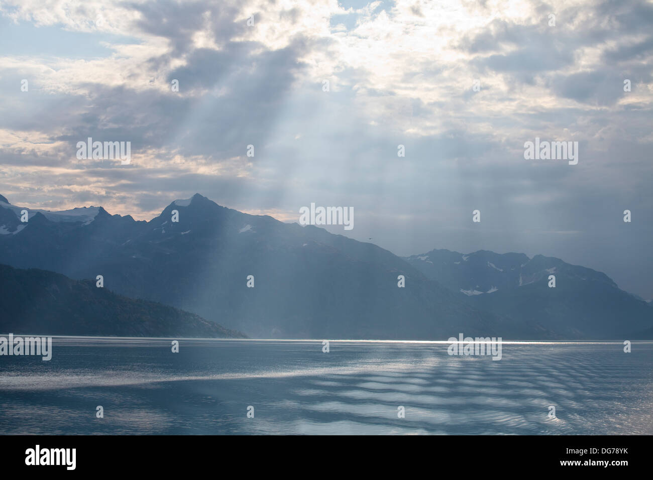Streaming di luce del sole attraverso le nuvole nel Glacier Bay in Alaska, durante una crociera in Alaska. Foto Stock