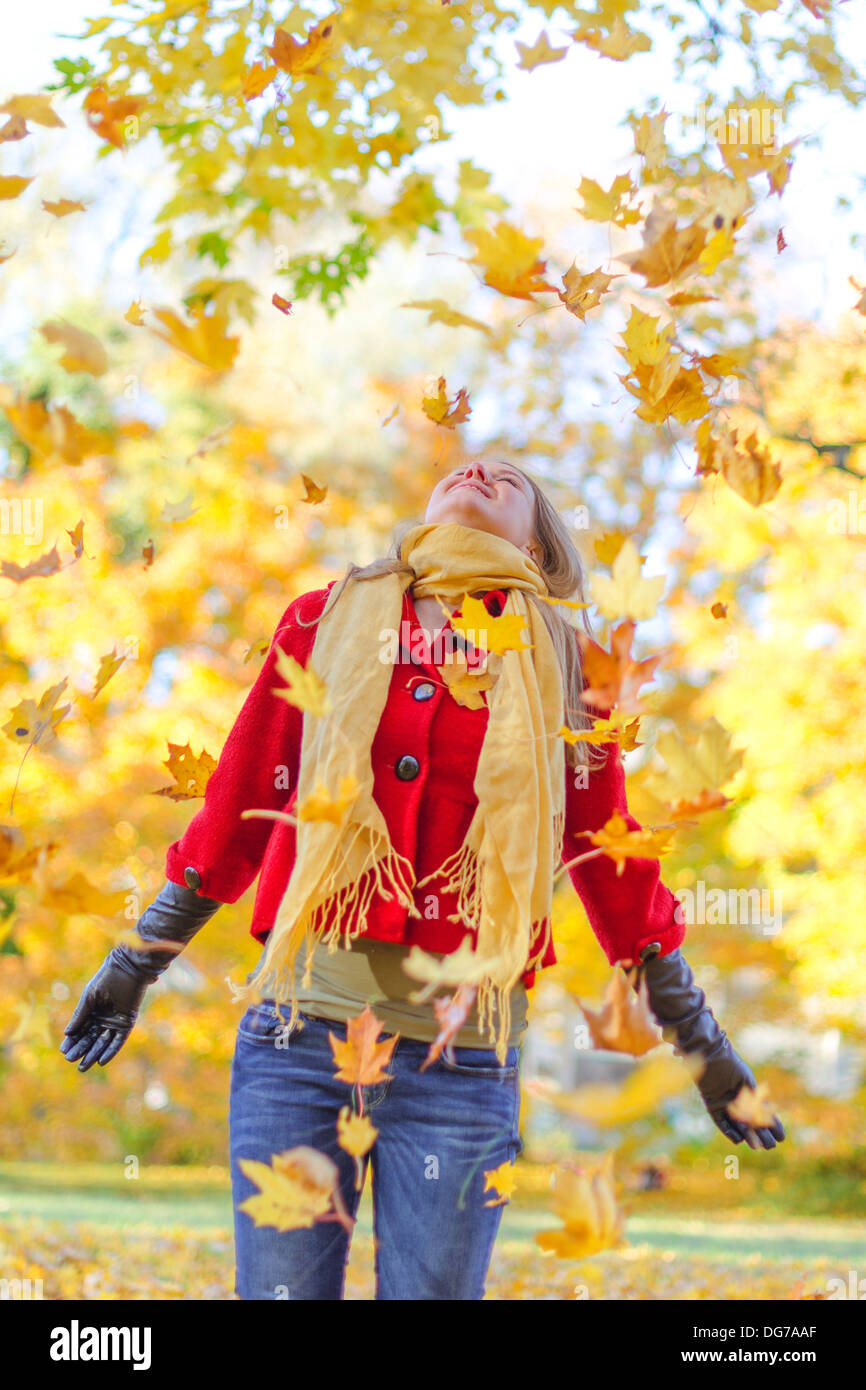 Donna felice gettando le foglie di autunno nel parco. Foto Stock