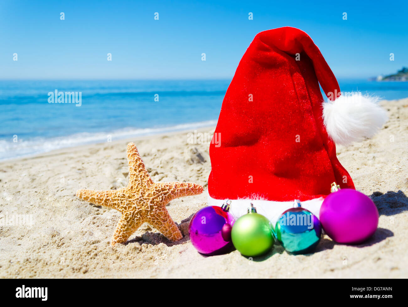 Starfish con cappello di Natale e le sfere sulla spiaggia dall'oceano - Concetto di vacanza Foto Stock