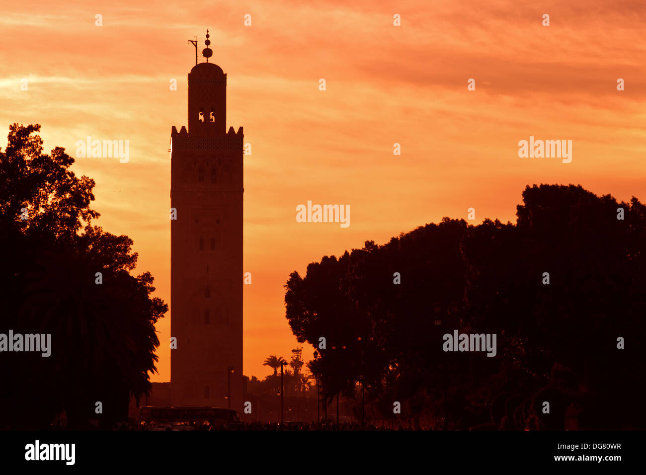Silhouette di un minareto al tramonto di Marrakech, Marocco contro un luminoso cielo arancione Foto Stock