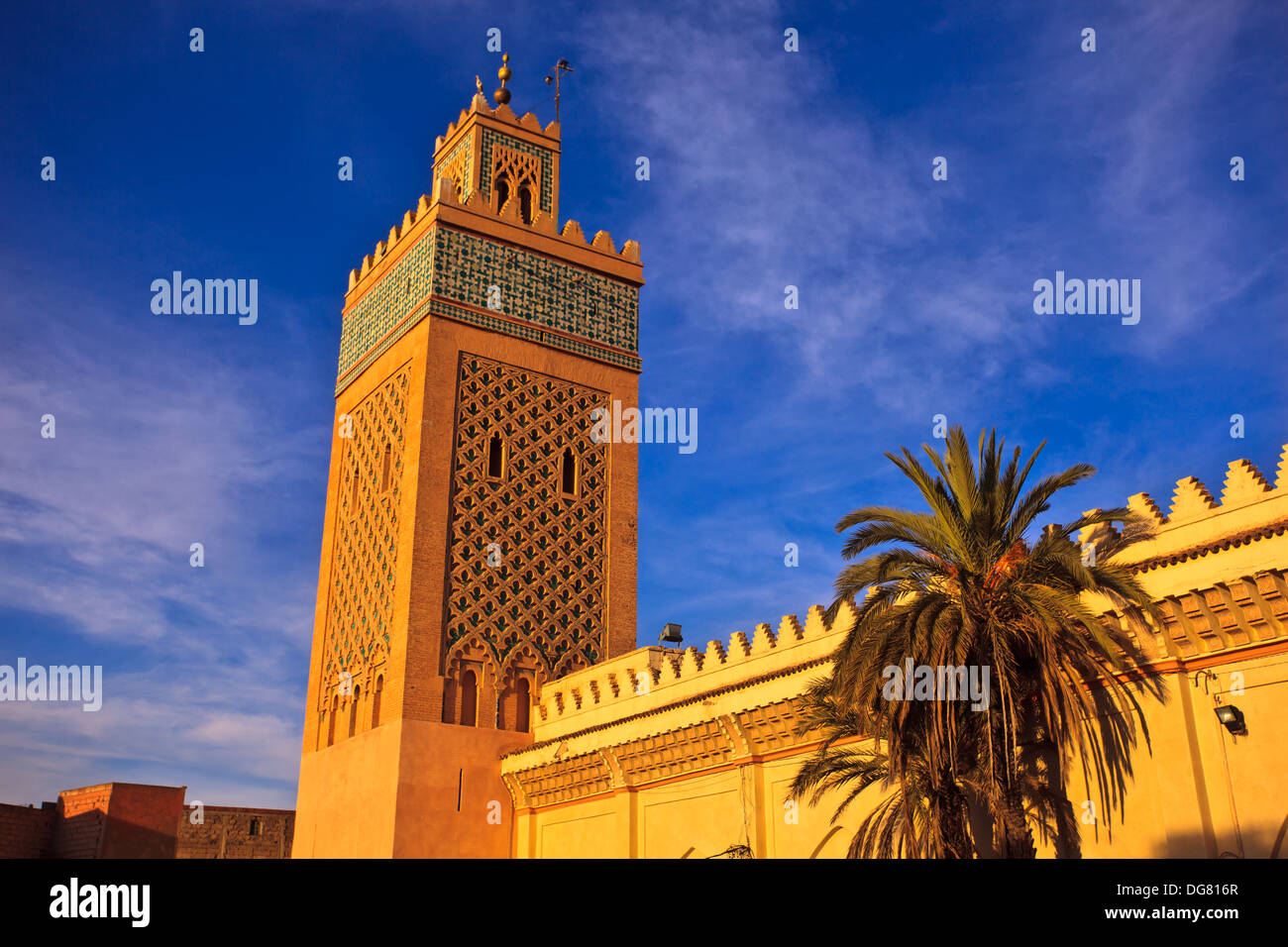 Minareto ornati sorge sopra le pareti della moschea nel cielo blu di Marrakech, Marocco Foto Stock