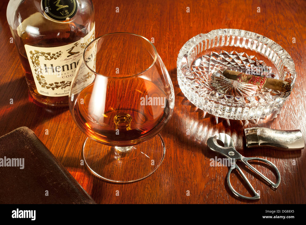 Il Brandy e sigari - snifter un bicchiere di brandy Hennessy con una parte fumato il sigaro nel portacenere Foto Stock