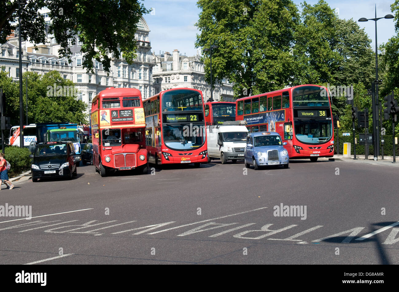 Una miscela di autobus e taxi tirare lontano da un semaforo a Hyde Park Corner, Londra. Foto Stock