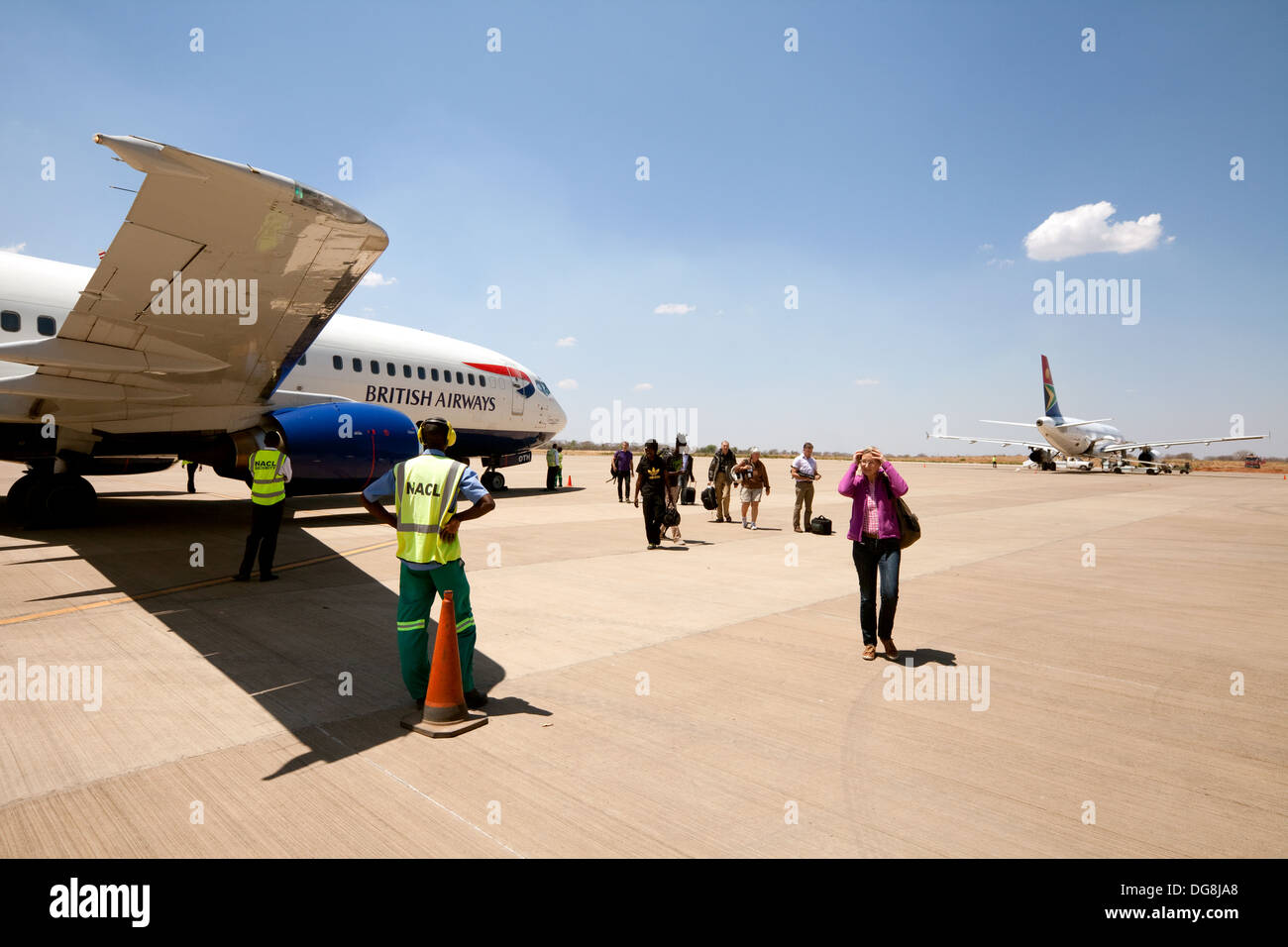 La gente lo sbarco da un British Airways Boeing 737 su asfalto a Livingstone airport, Zambia, Africa Foto Stock