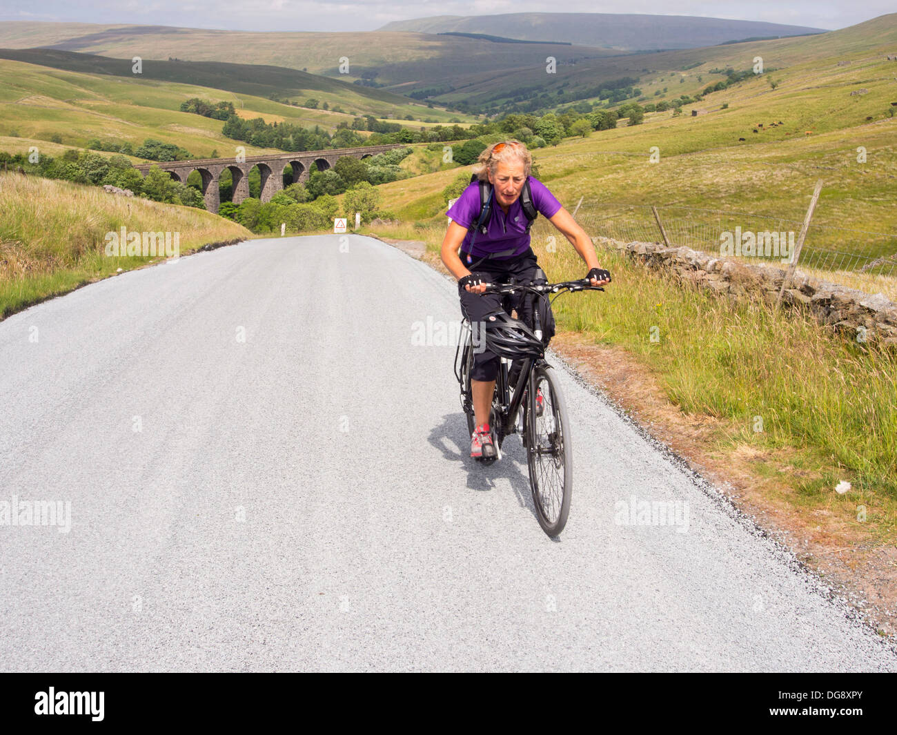 Una donna il cicloturismo, equitazione fuori Dentdale nel Yorkshire Dales National Park, Regno Unito. Foto Stock