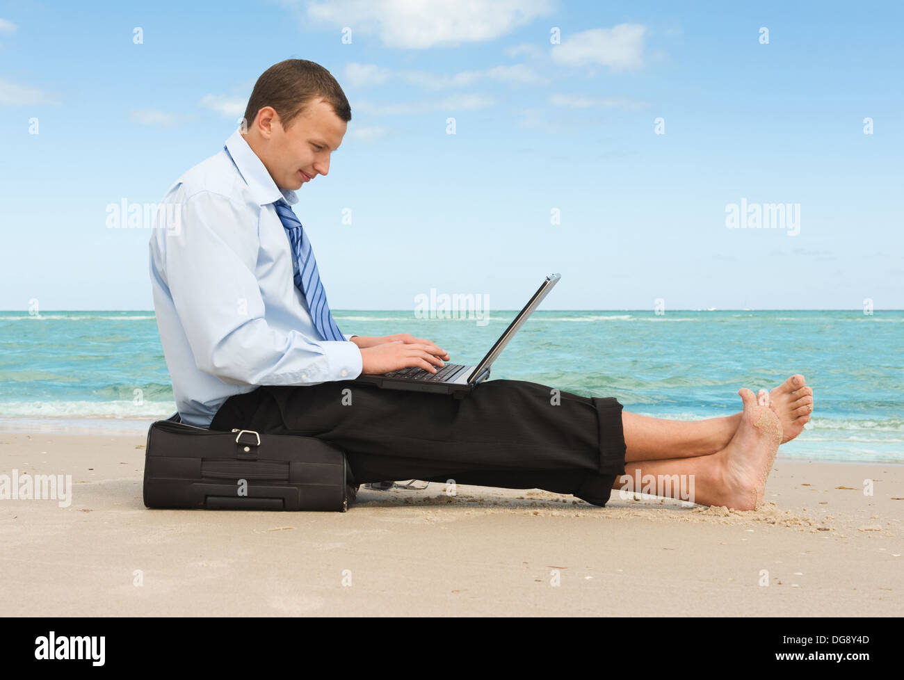 Giovane imprenditore lavora con il computer portatile sulla spiaggia Foto Stock