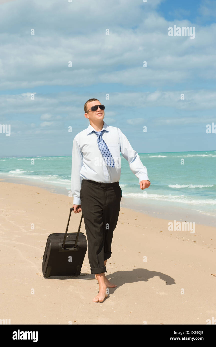Imprenditore di camminare sulla spiaggia il primo giorno di vacanza Foto Stock