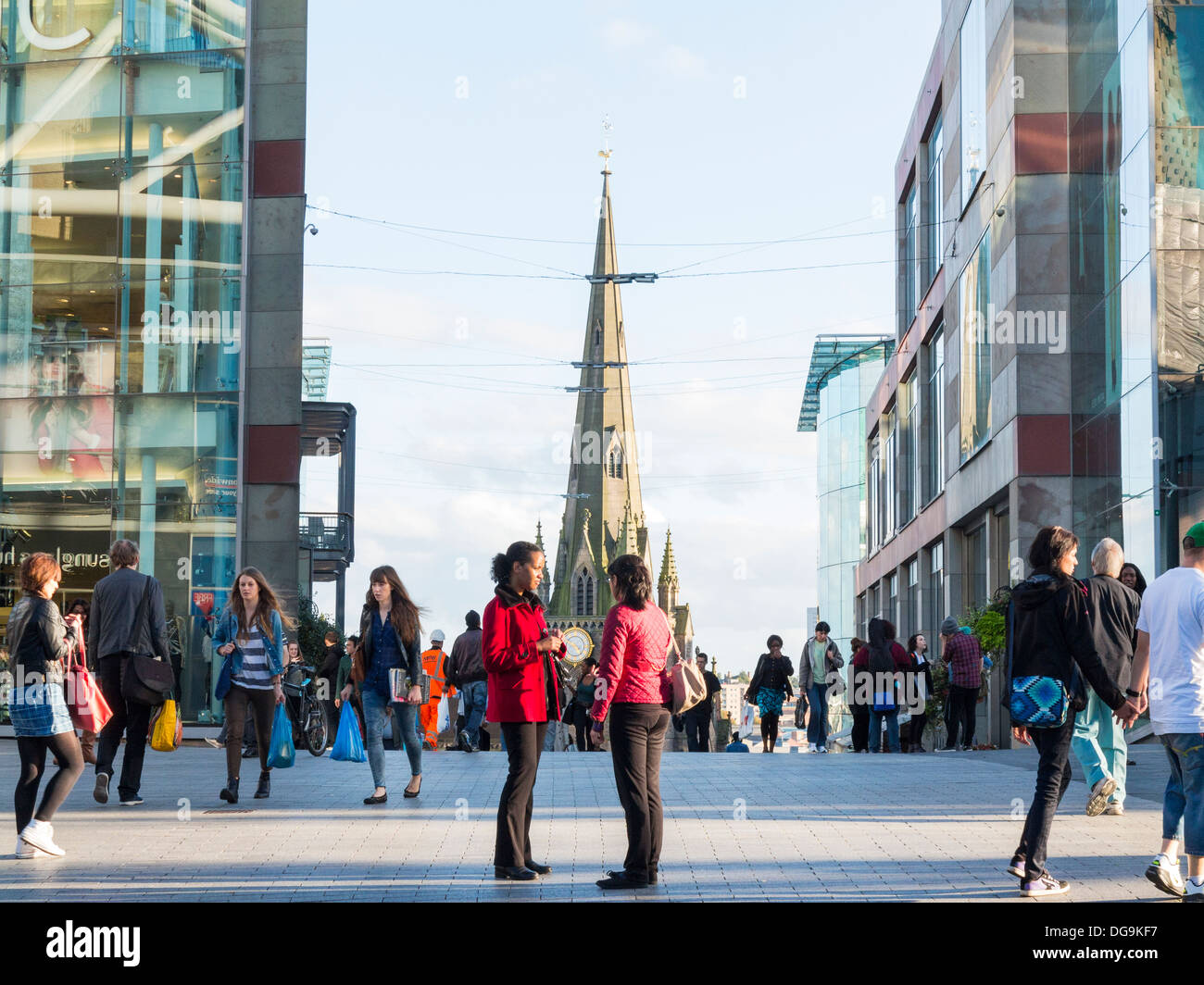 La gente di socializzare nell'Arena Center con St Martin's Church dietro, Birmingham, Midlands, Inghilterra Foto Stock