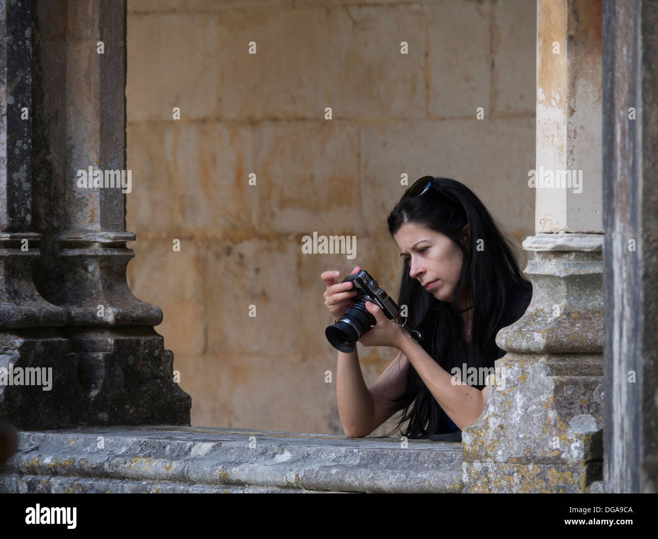 Giovane donna guardando il display LCD sul retro della sua fotocamera digitale durante la ripresa di immagini Foto Stock