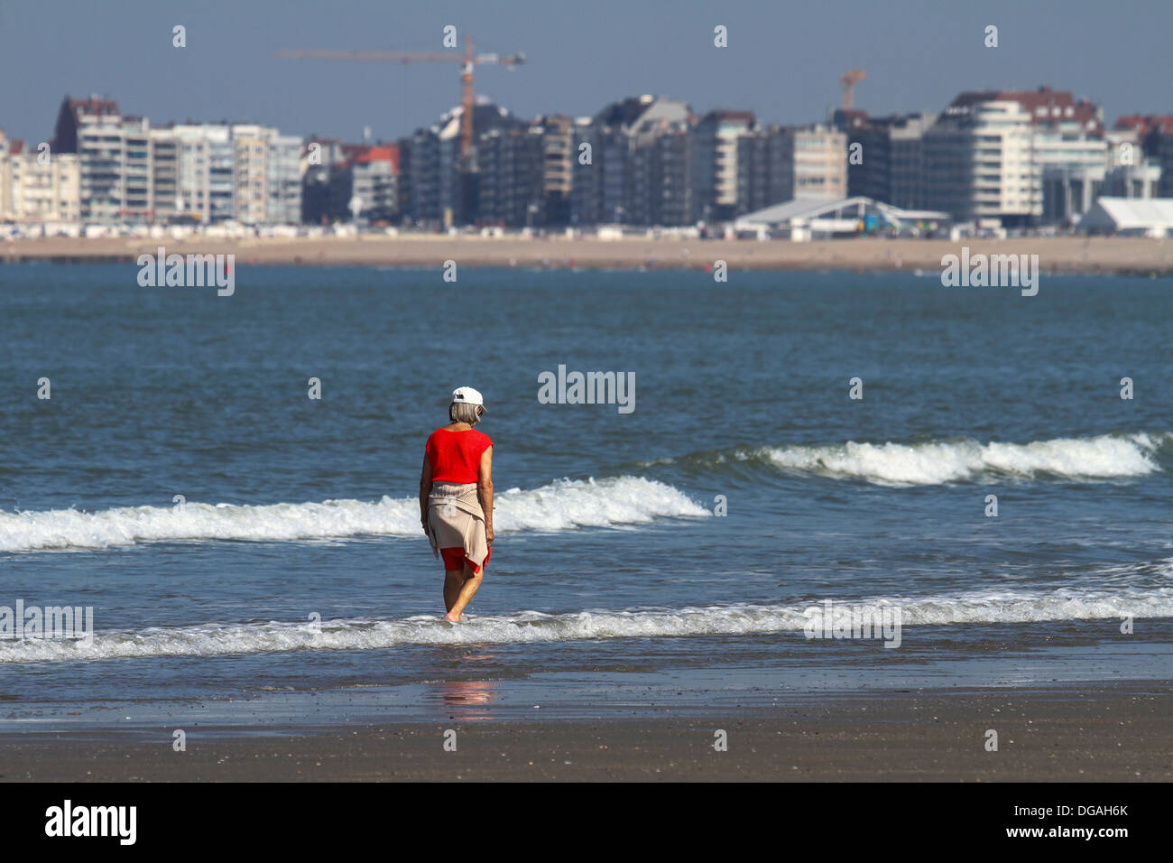 Vista su appartamenti della località balneare e turistico anziani sguazzare in acqua di mare del Nord lungo la spiaggia in estate Foto Stock