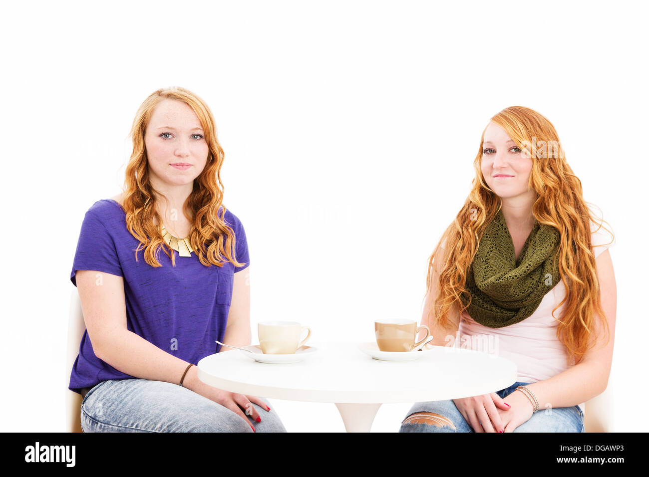Affascinante redhead giovani donne seduti ad un tavolo da caffè su sfondo bianco Foto Stock