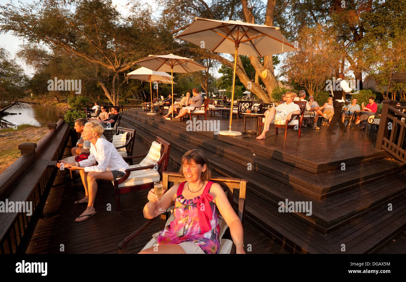 Gli ospiti dell'hotel e guardare il tramonto dal tramonto veranda bar, Royal Livingstone Hotel Victoria Falls, Zambia Africa Foto Stock