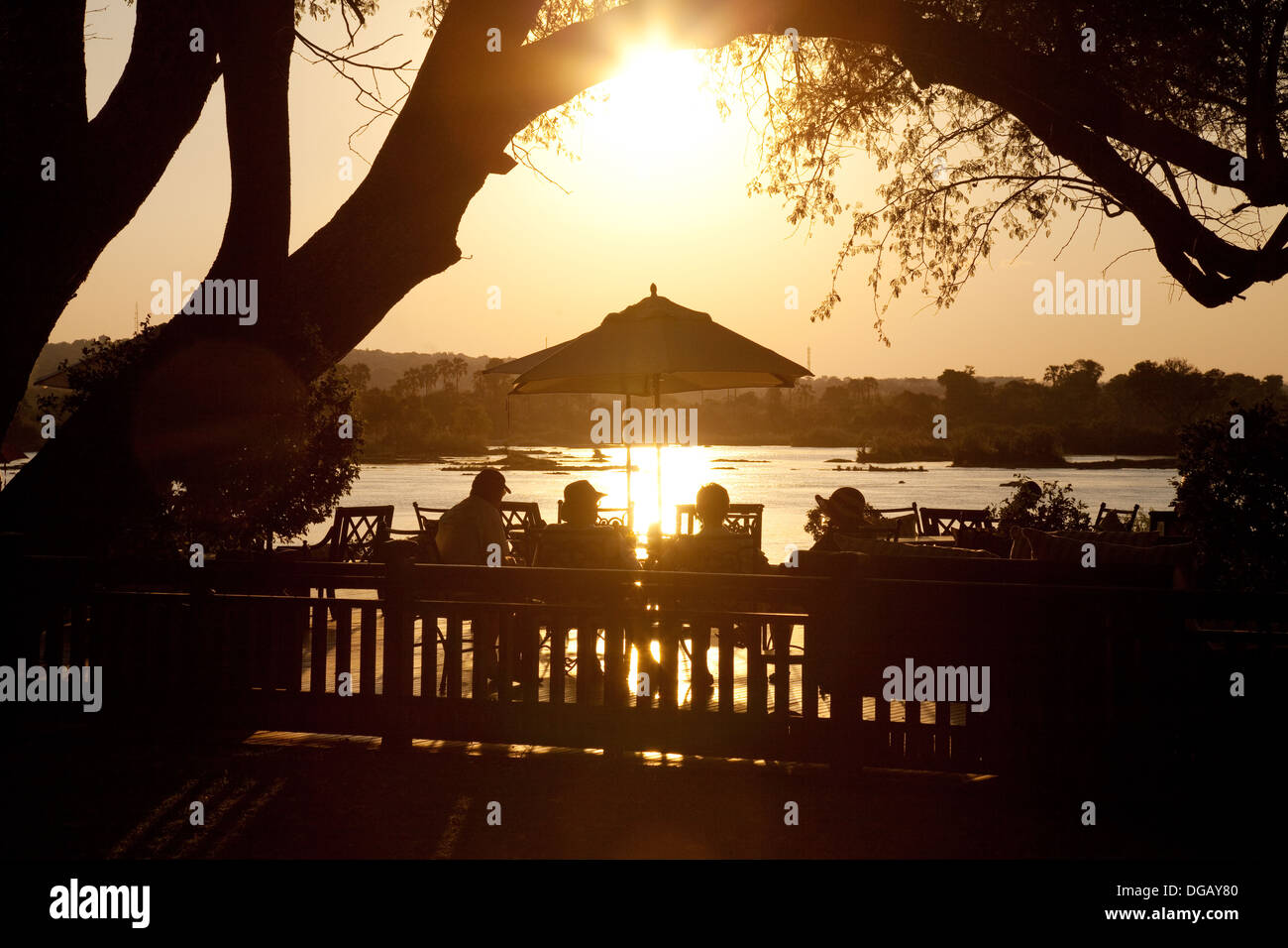 Gli ospiti sulla veranda al tramonto guardando il tramonto sul fiume Zambesi, Royal Livingstone Hotel, Zambia Africa Foto Stock