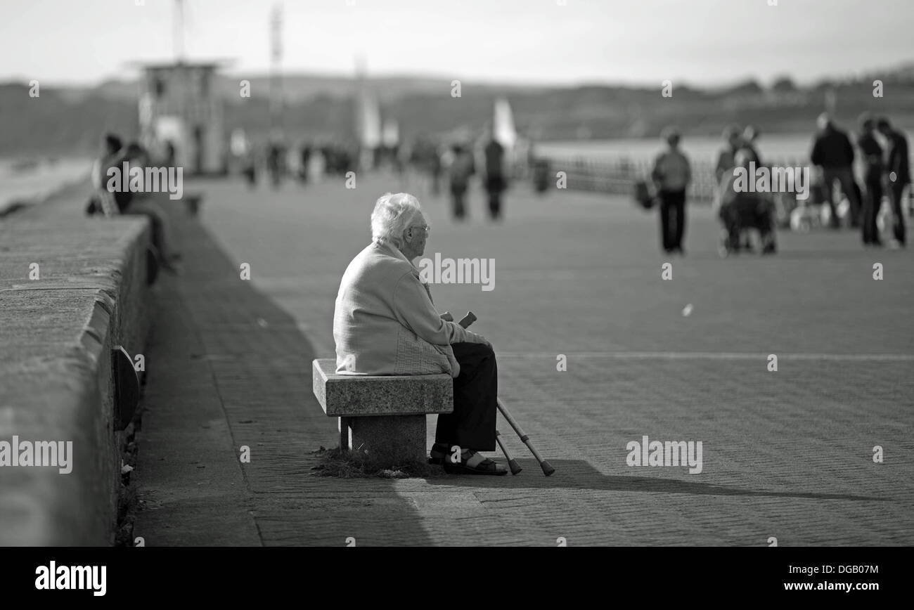 Old Lady da soli Mountbatten Pier Plymouth seduta con bastoni da passeggio in bianco e nero Foto Stock