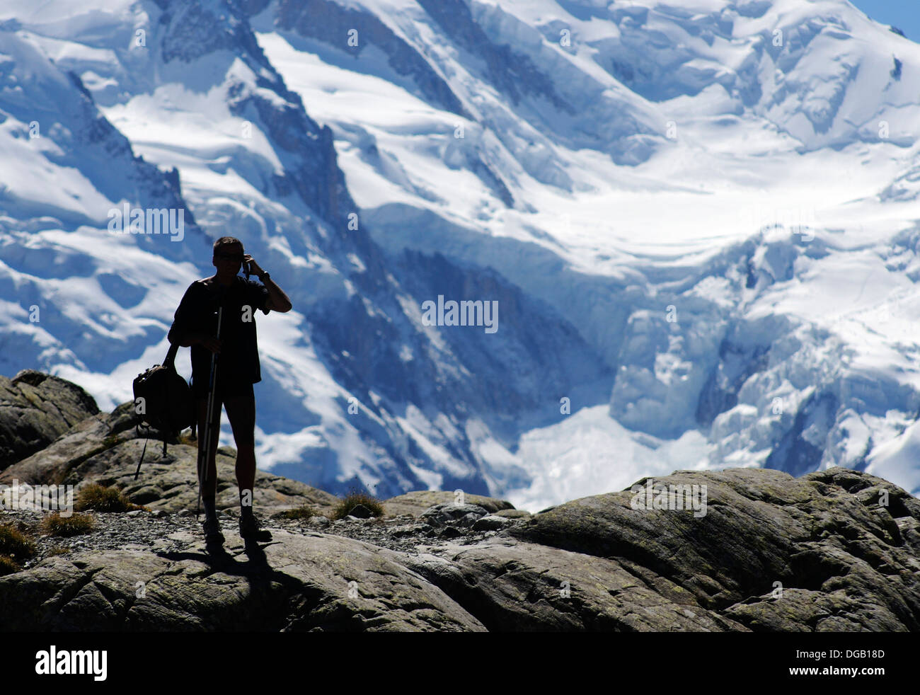 Un hillwalker utilizzando un telefono cellulare nelle Alpi, con Mont Blanc dietro Foto Stock