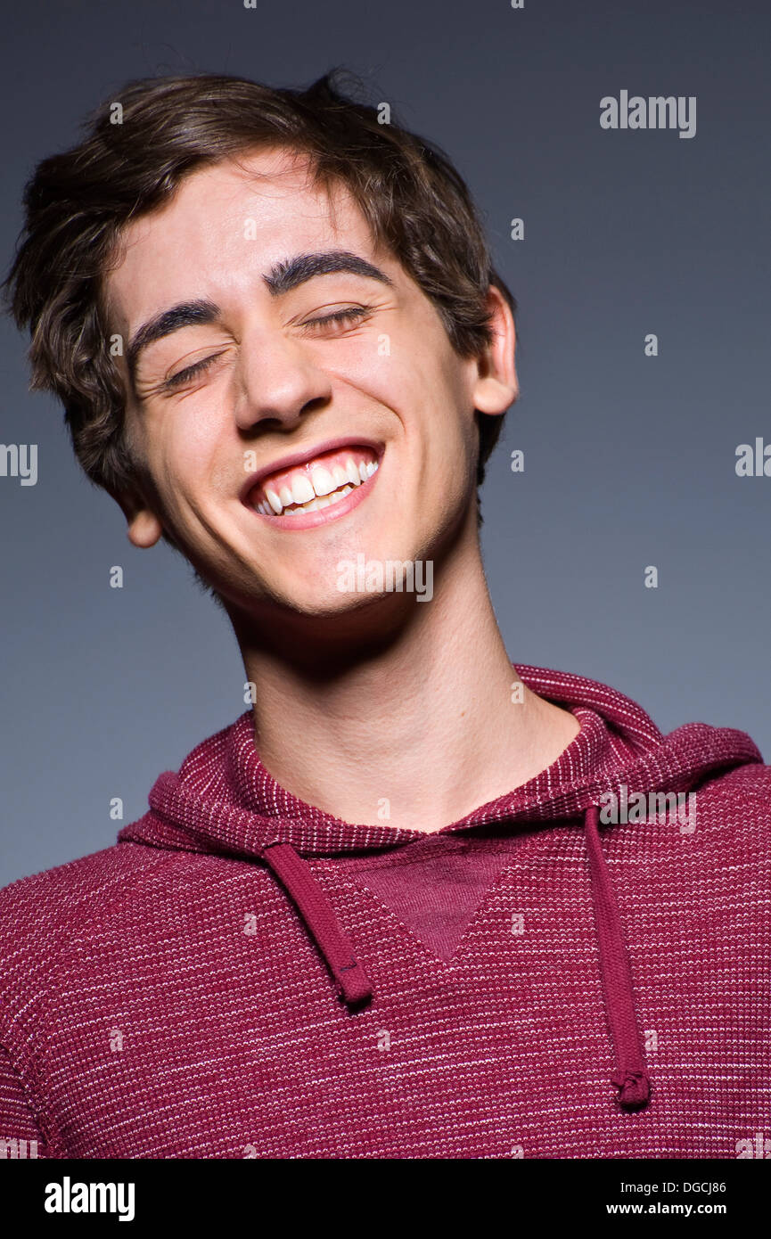 Giovane uomo a ridere con gli occhi chiusi, studio shot Foto Stock
