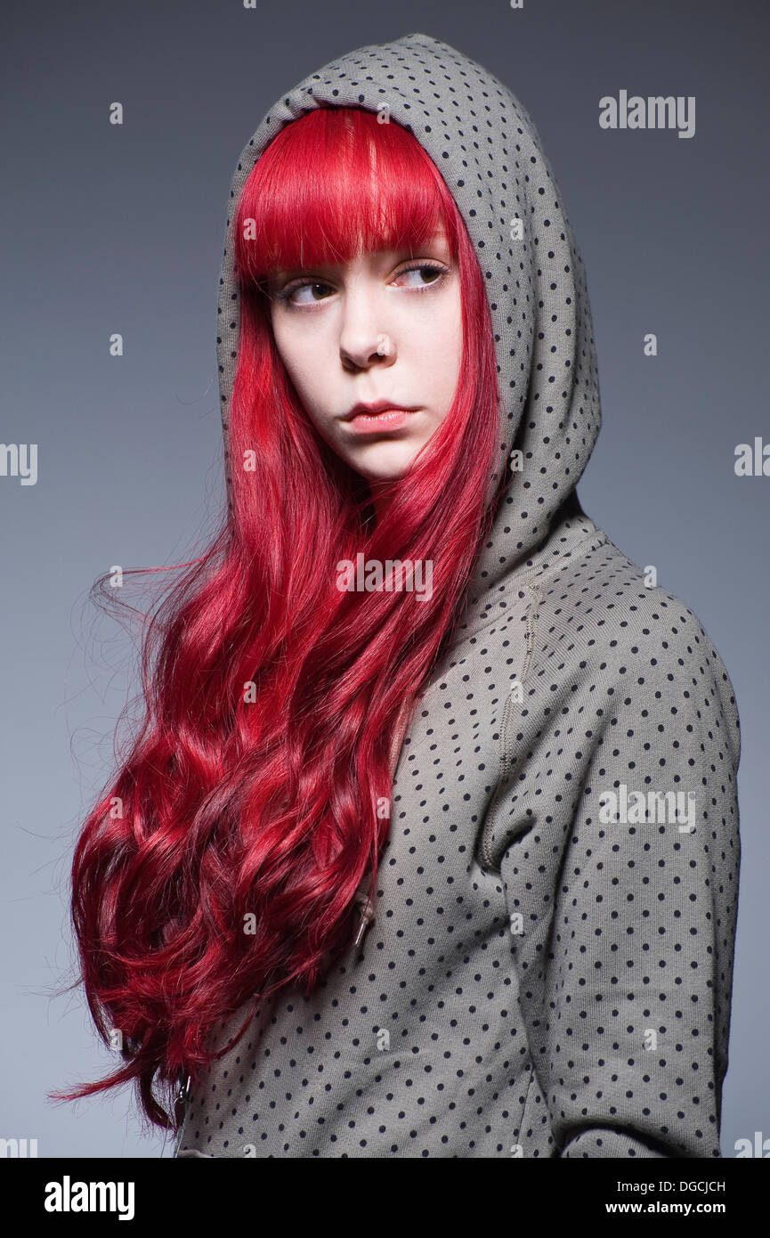 Giovane donna con lunghi capelli rossi in top con cappuccio Foto Stock