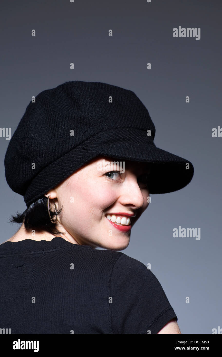 Giovane donna in black hat sorridente, ritratto Foto Stock