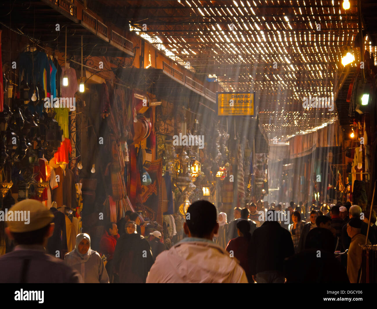 Striature di luce del sole verso il basso sul shopper affollano il Grand Bazaar souk di Marrakech in una giornata di sole Foto Stock