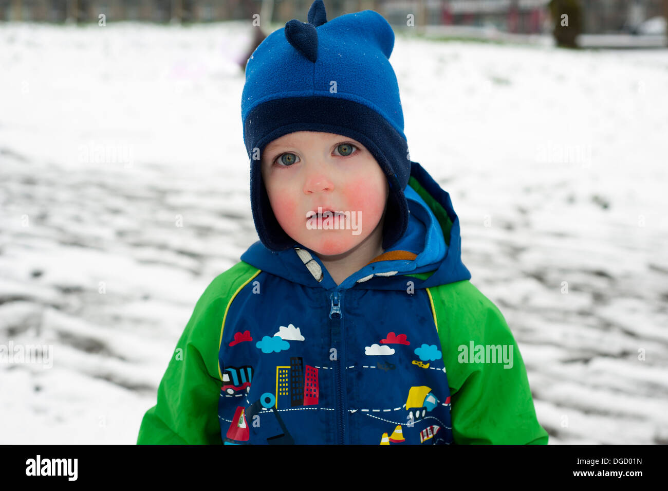 Ragazzo che indossa cappellino con le guance rosse nel parco innevato Foto Stock