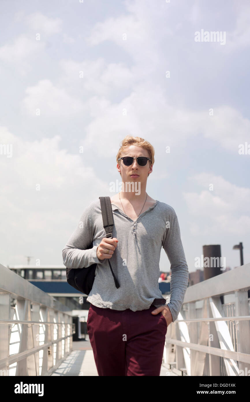 Giovane uomo che cammina sulla passerella di Brooklyn, a New York City, Stati Uniti d'America Foto Stock