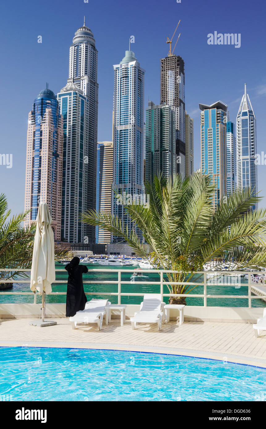Dubai Marina viste di una donna che indossa guardando sopra i grattacieli di Dubai Marina, dalla piscina di un hotel, Dubai, Emirati Arabi Uniti Foto Stock