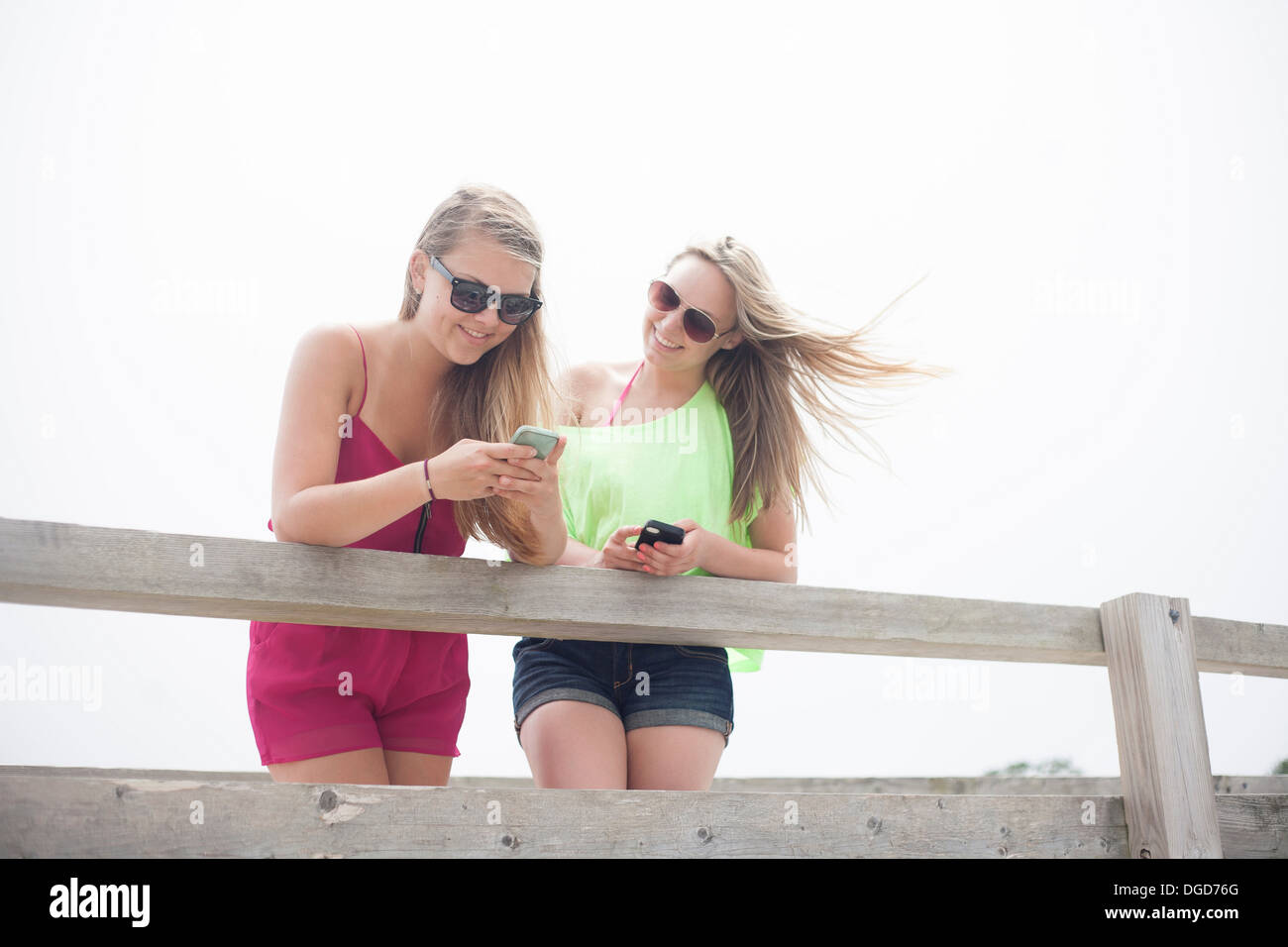 Giovani donne che utilizzano i telefoni cellulari sul molo Foto Stock