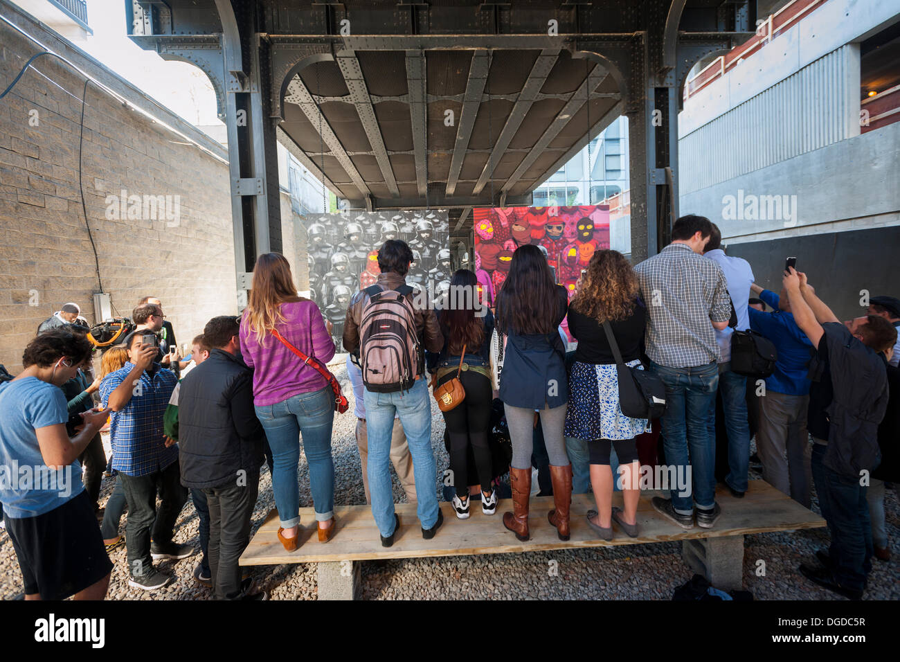 New York, Stati Uniti d'America. Il 18 ottobre 2013. Street appassionati d arte gregge del quartiere alla moda di West gallery Chelsea District di New York per vedere il diciottesimo episodio di Banksy dell arte dei graffiti, una collaborazione con gli artisti brasiliani, Os Gemeos. Questa quota è impostato come un museo in un vuoto di partita sotto la linea alta Park completo di 'Museum' protezioni per la maniglia di controllo della folla. Il fantomatico artista di strada è la creazione di opere intorno alla città ogni giorno durante il mese di ottobre. Credito: Richard Levine/Alamy Live News Foto Stock