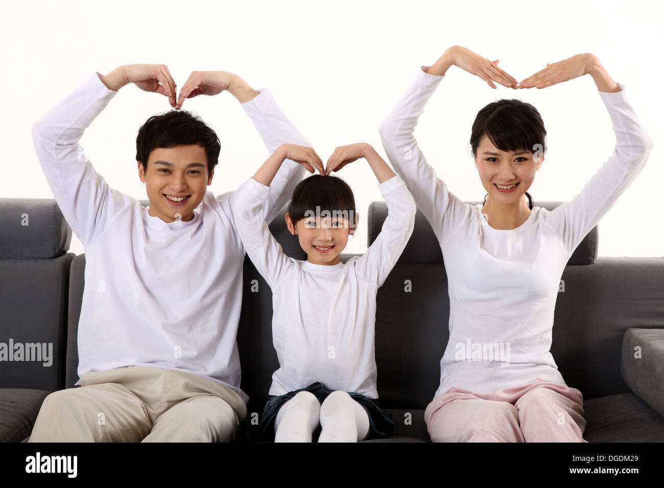 Oriente famiglia asiatica con un bambino seduto sul divano, mettendo a forma di cuore, sorridente, guardando la telecamera Foto Stock