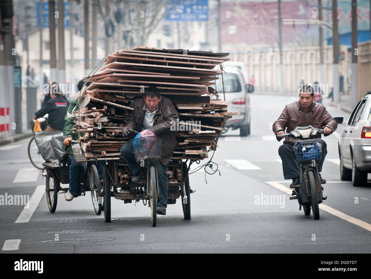 Uomo che porta mucchio di vecchie schede madri dei rifiuti e tavole su tre ruote di ciclo con carrello su strada a Shanghai in Cina Foto Stock