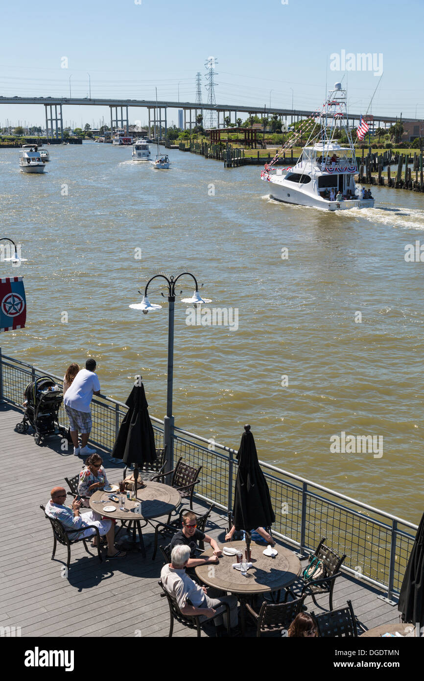 I turisti di mangiare fuori a Kemah Boardwalk Amusement Park come barche a vela passato Foto Stock