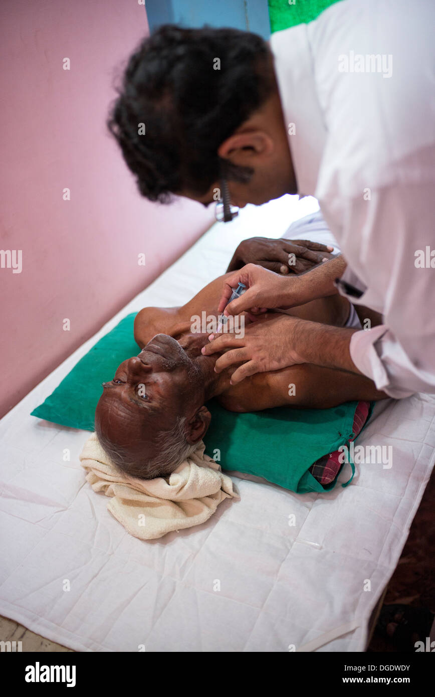 L'aspirazione con ago fine patologo estrazione delle celle in un grumo di un paziente di sesso maschile a Sathya Sai Mobile Ospedale outreach Foto Stock