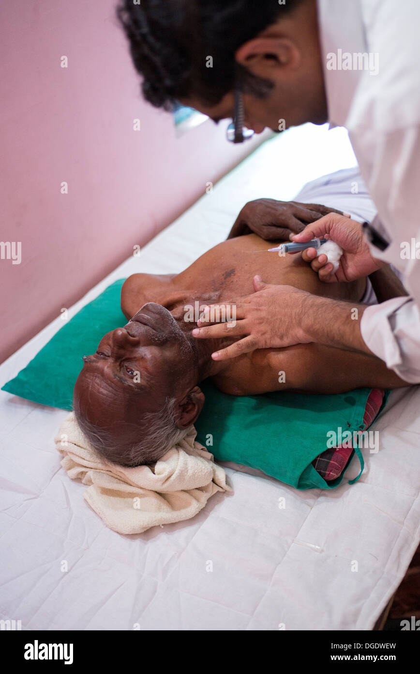 L'aspirazione con ago fine patologo sensazione un grumo sul collo di un paziente di sesso maschile a Sathya Sai Mobile Ospedale outreach Foto Stock