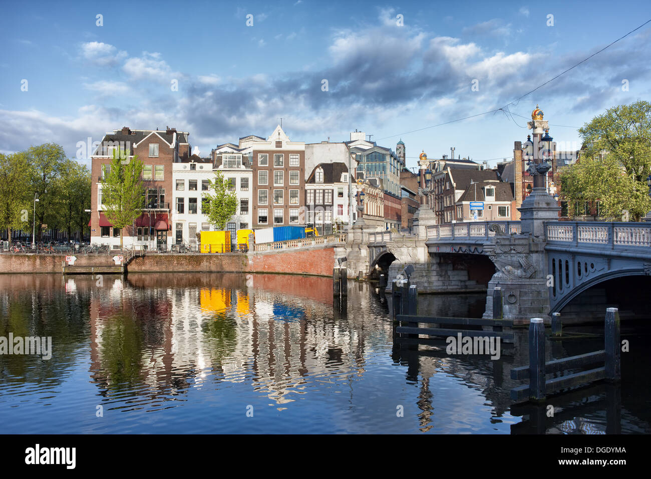 Case con riflessioni sul fiume Amstel acque nella città di Amsterdam, Paesi Bassi, Blue Bridge (Blauwbrug) sulla destra. Foto Stock