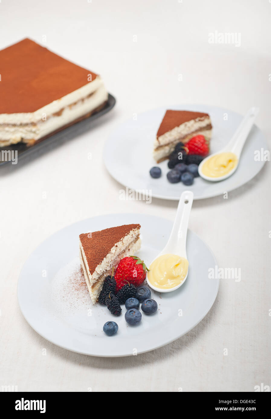 Italiano classico tiramisù dessert con bacche e custartd crema pasticcera sul lato Foto Stock