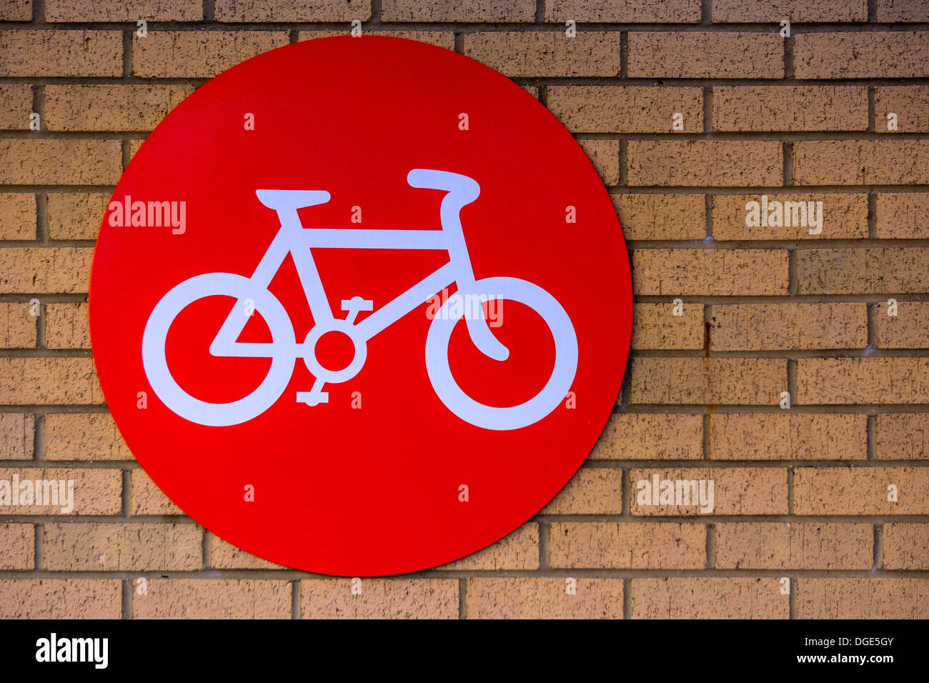 Un parco biciclette sul segno rosso di un muro di mattoni. Foto Stock